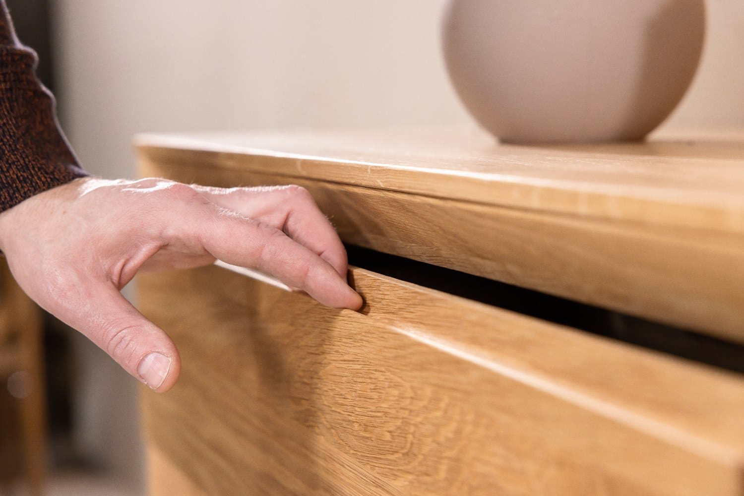 Hand opening the drawer of a solid oak chest